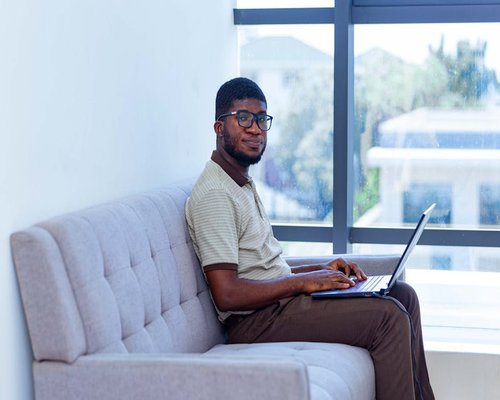 Young professional working comfortably on a laptop by a window with soft natural light