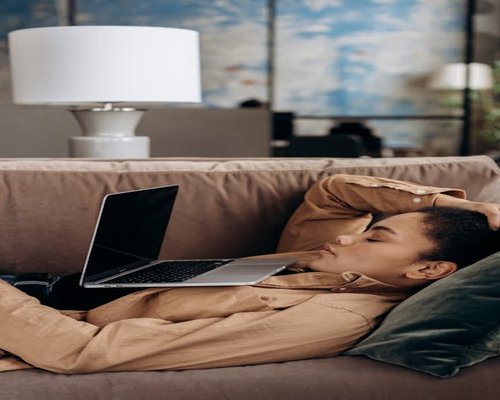 Person resting eyes by looking away from the laptop screen towards a room interior