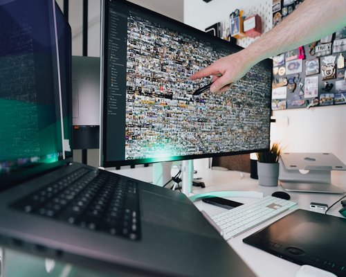 Hand adjusting the brightness settings on a computer monitor